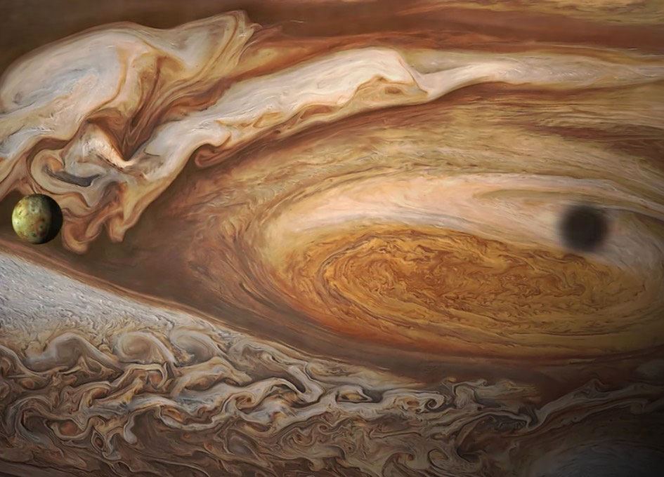 This photograph was taken by the Juno spacecraft. It depicts a moon against the swirling cloud cover of the planet Jupiter. Jupiter and moon